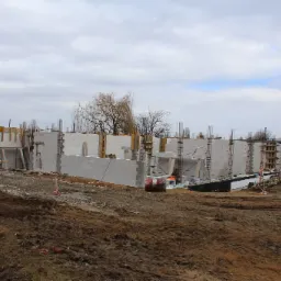 Wznoszenie ścian parteru z betonu komórkowego Ytong Silka na budowie przedszkola pasywnego; widoczne zbrojenia i drewniane szalunki.