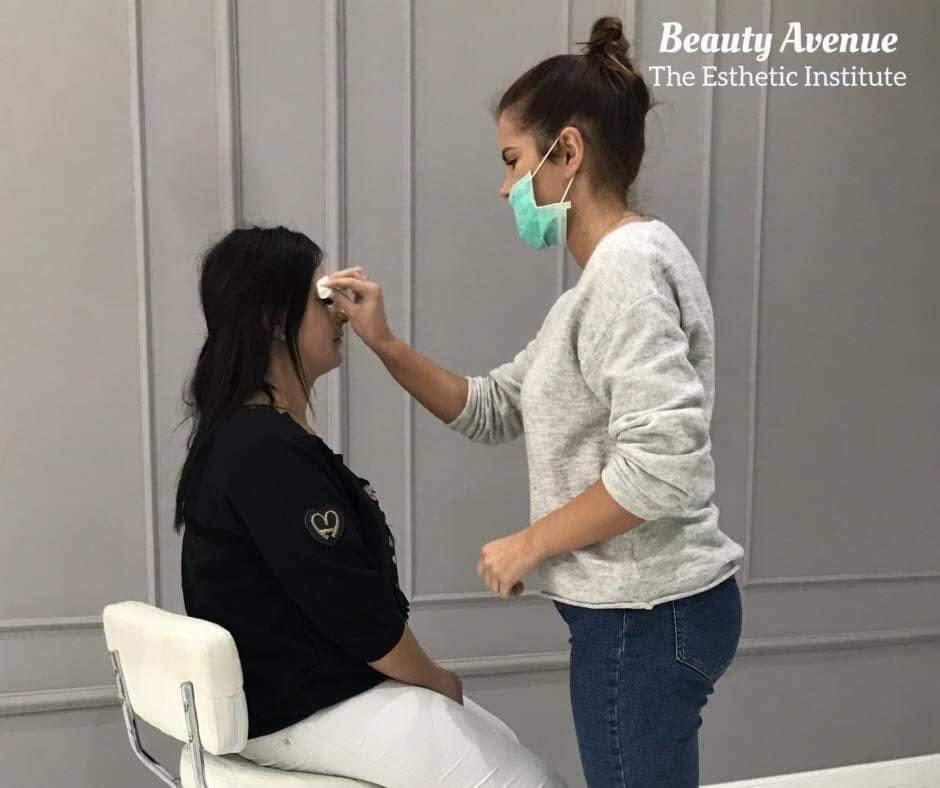 Kosmetyczka w maseczce delikatnie oczyszcza skórę klientki w salonie, przygotowując ją do zabiegu upiększającego.