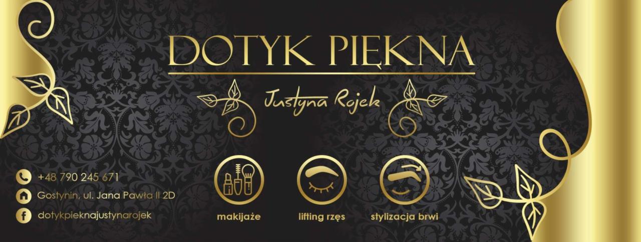 Wizytówka salonu kosmetycznego z nazwą 'Dotyk Piękna Justyna Rojek', złotymi ikonami usług (makijaż, lifting rzęs, stylizacja brwi) na czarnym, wzorzystym tle i złotym paskiem z prawej strony.