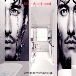 Nowoczesna łazienka w bieli z fototapetą przedstawiającą męską twarz, rower w korytarzu i pralka w tle.