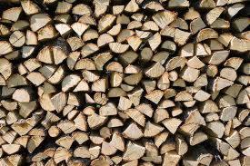 Równomiernie ułożone, pocięte kawałki drewna opałowego, widoczne słoje i naturalna barwa drewna.