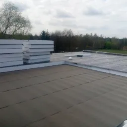 Prace związane z ociepleniem dachu w Zmysłówce: widok na rozłożoną papę termozgrzewalną i ułożone płyty izolacyjne z polistyrenu ekstrudowanego.