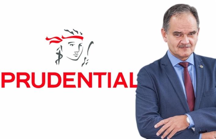 Mężczyzna w garniturze stoi na tle logo firmy Prudential.