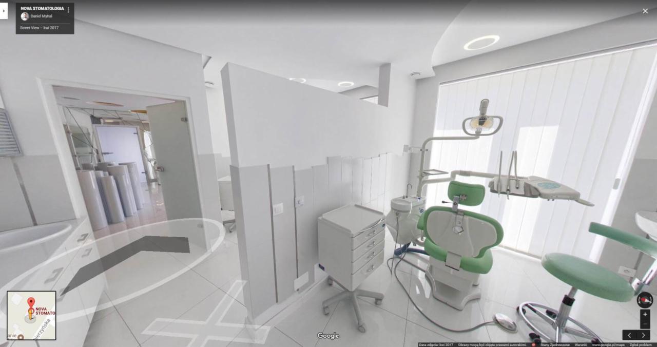 Wnętrze gabinetu stomatologicznego z białymi ścianami, zielonym fotelem dentystycznym i sprzętem medycznym, widoczne pionowe żaluzje w oknie.