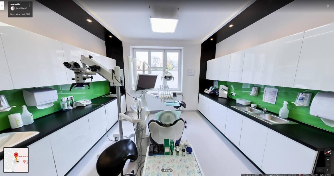 Wnętrze gabinetu stomatologicznego z nowoczesnym sprzętem, w tym mikroskopem i unit stomatologicznym, białe szafki z czarnymi blatami i zielonymi panelami, widok z perspektywy pacjenta.