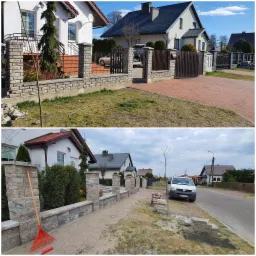 Budowa ogrodzenia z kamienia łupanego, widoczne słupki i podmurówka w trakcie montażu, na drugim planie domy jednorodzinne, grabie i paleta z kamieniami obok