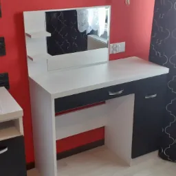 Toaletka z lustrem i półkami, biało-czarna, z widocznym fragmentem grzejnika i wzorzystej zasłony w tle.