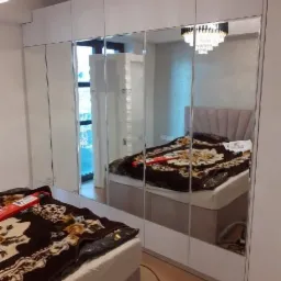 Biała szafa wnękowa z lustrzanymi drzwiami, odbijająca sypialnię z łóżkiem i żyrandolem, Maciejów Nowy.