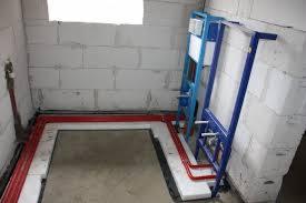 Stelaż podtynkowy WC zamontowany przy ścianie z betonu komórkowego, z widocznymi czerwonymi rurami instalacji wodnej w podłodze, przygotowany do dalszych prac wykończeniowych.