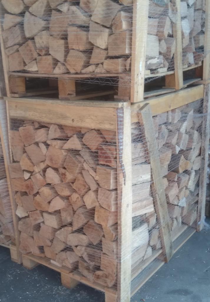 Ułożone drewno w skrzyniopaletach z siatką, przygotowane do transportu lub magazynowania.