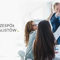 Zespół profesjonalistów świętuje sukces układając dłonie w górze, widoczne uśmiechnięte twarze i plany na stole.