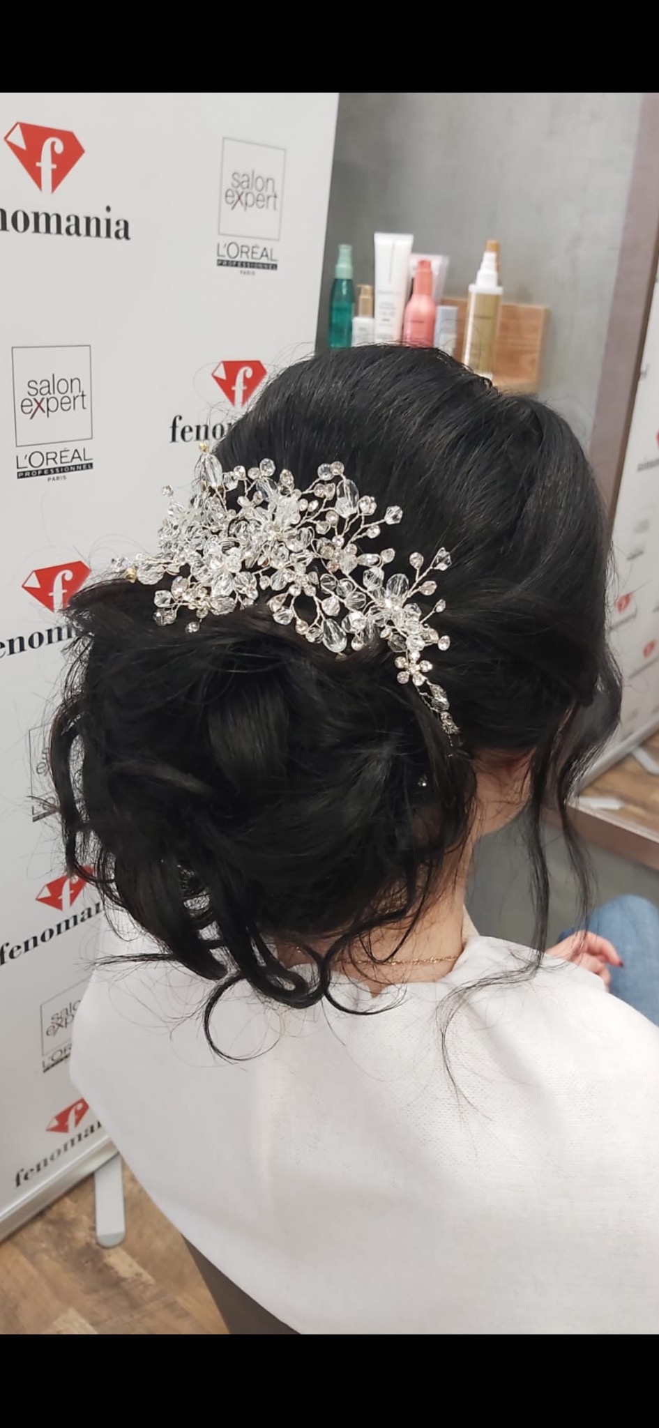 Upięcie włosów z ozdobnym, kryształowym diademem na ciemnych włosach, widok z tyłu, w tle logo salonu.