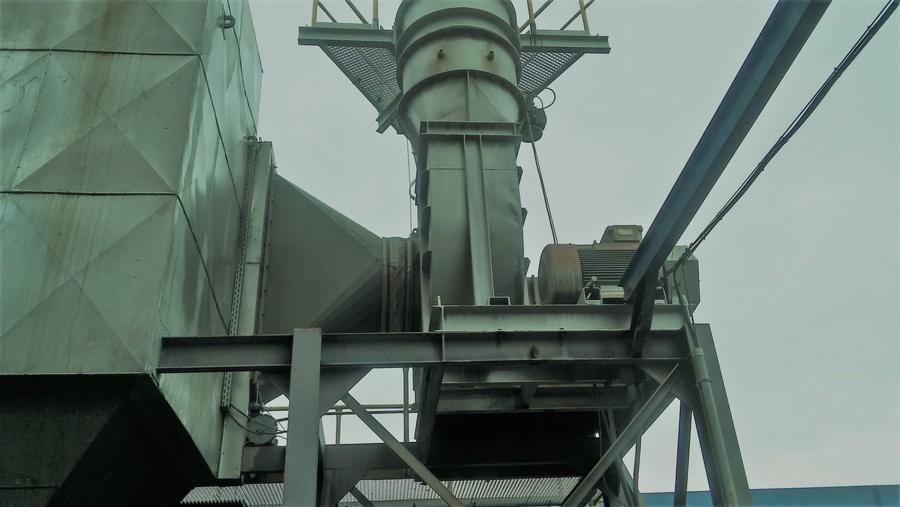 Skomplikowana, przemysłowa instalacja wentylacyjna z metalowymi kanałami, silnikiem i platformą, widziana z dołu pod kątem.