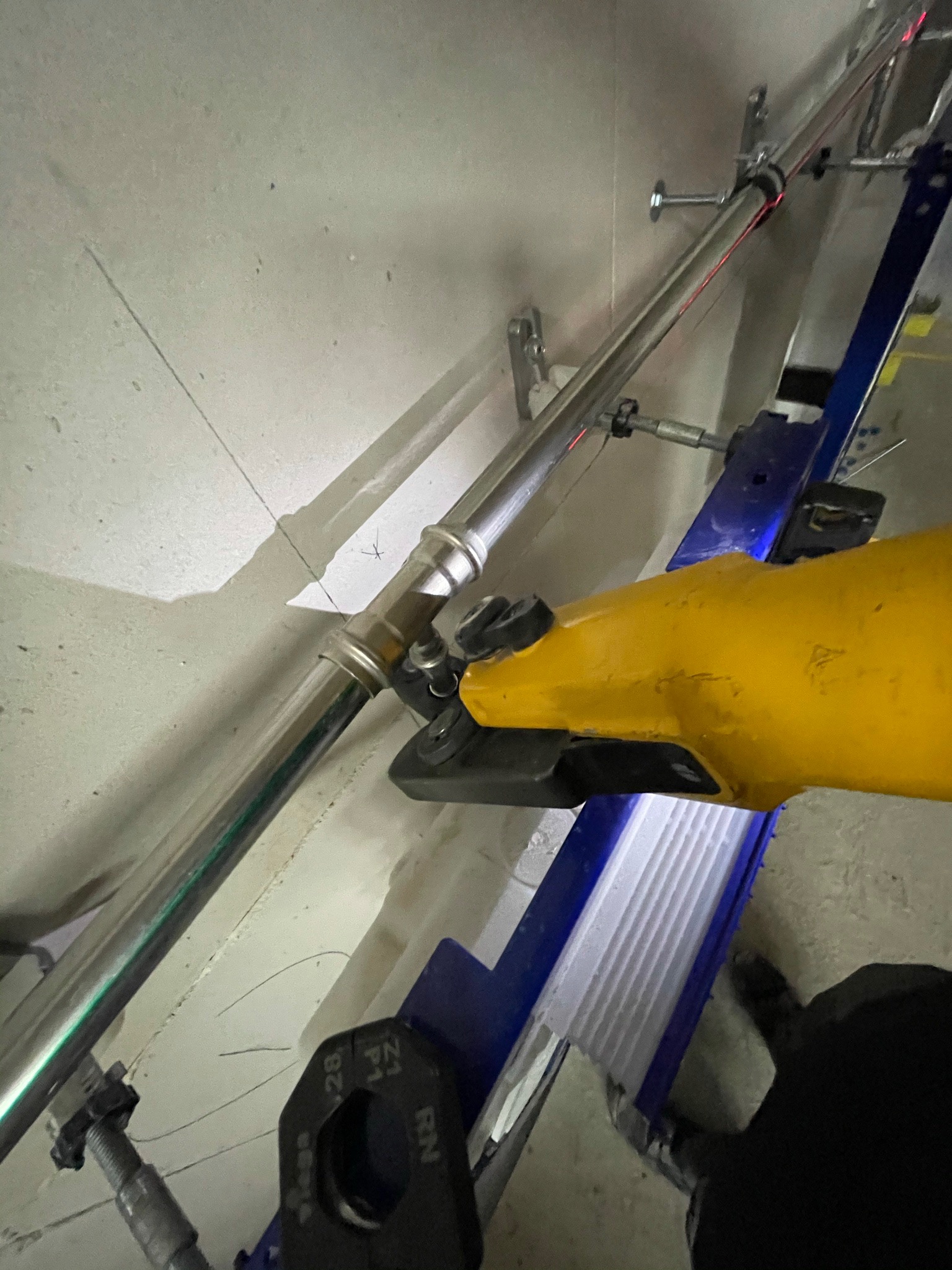 Instalacja rury z użyciem zaciskarki hydraulicznej na drabinie w surowym wnętrzu.