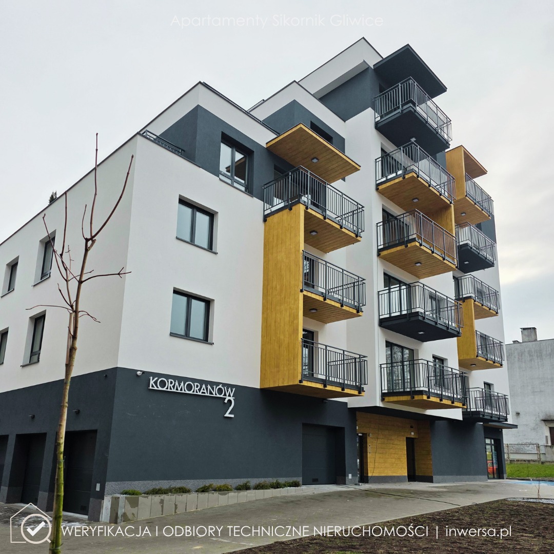 Nowoczesny apartamentowiec z balkonami i elementami z drewna, nazwa ulicy 'Kormoranów 2' w Gliwicach, widok z dołu, pochmurne niebo.