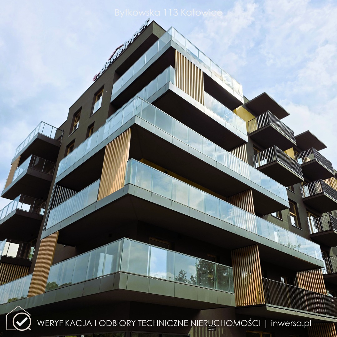 Nowoczesny budynek mieszkalny z balkonami z przeszkleniami, widziany pod kątem, z logo dewelopera na dachu i oznaczeniem odbiorów technicznych w rogu.