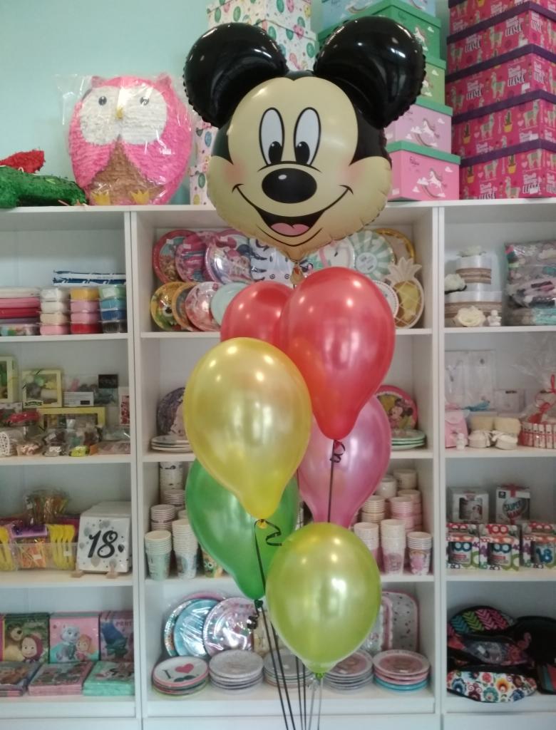 Bukiet balonów z folii w kształcie Myszki Miki i lateksowych balonów w kolorach zielonym, żółtym, czerwonym i różowym na tle regału z dekoracjami i akcesoriami imprezowymi w sklepie w Nowym Targu.