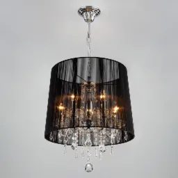 Elegancki żyrandol z czarnym abażurem z delikatnej tkaniny i kryształowymi elementami, zawieszony na srebrnym łańcuchu, oświetlony ciepłym światłem