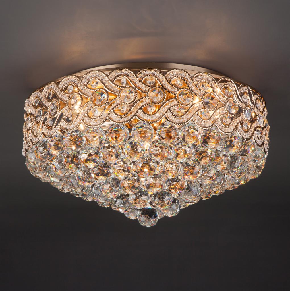 Kryształowy plafon sufitowy z ozdobną, złotą ramą i delikatnym podświetleniem, widok z dołu.