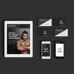 Mockup prezentujący identyfikację wizualną firmy Wolver: logo na tablecie, smartfonach oraz wizytówki z motywem sportowym i wizerunkiem umięśnionego mężczyzny.