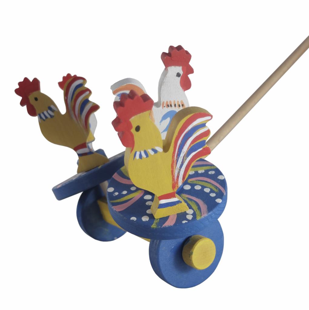 Drewniany wózek z trzema kolorowymi kogutami, ręcznie malowany, na białym tle.