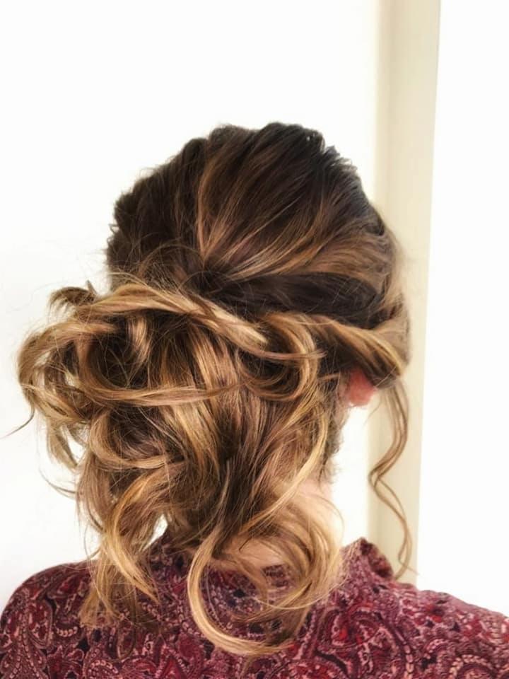 Upięcie włosów z brązowymi pasemkami, luźno spięte z tyłu głowy, widoczne pojedyncze, kręcone kosmyki opadające na ramiona, wzorzysta bluzka w odcieniach czerwieni.