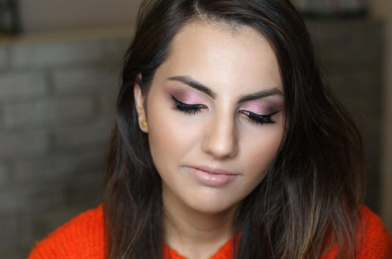 Kobieta z delikatnym makijażem oczu w odcieniach różu i czarnym eyelinerem, spoglądająca w dół.