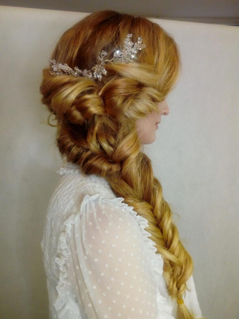 Profil kobiety z długimi, rudymi włosami upiętymi w gruby warkocz i ozdobionymi srebrną spinką z kryształkami.