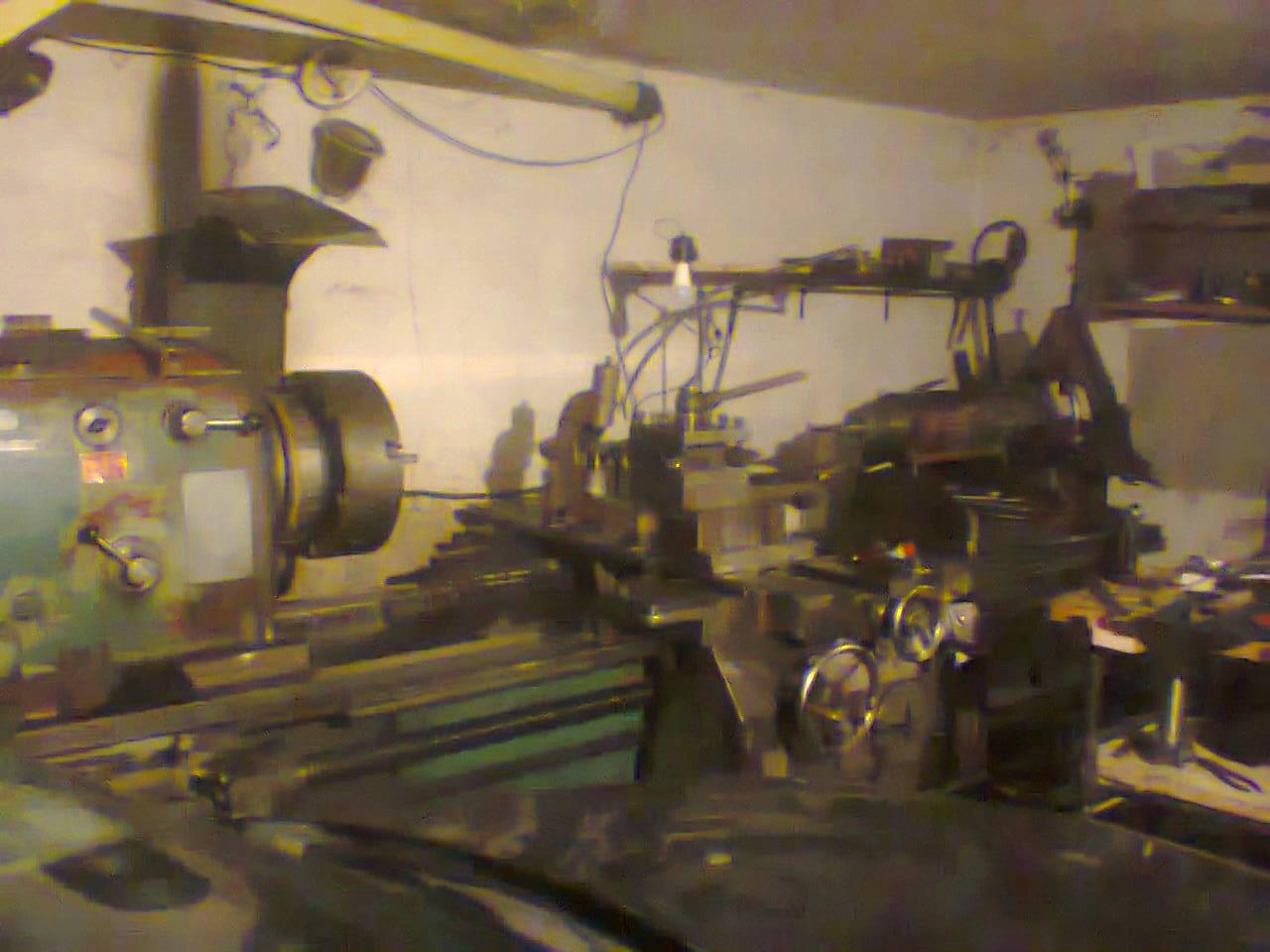 Stare, używane tokarki w warsztacie, widoczne ślady rdzy i zużycia, oświetlenie warsztatowe, narzędzia na półkach w tle.