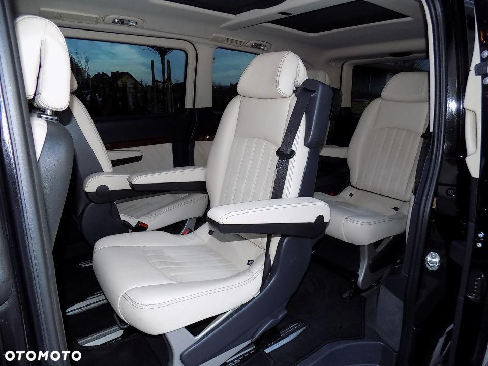 Wnętrze luksusowego vana z beżowymi skórzanymi fotelami, widoczne regulowane podłokietniki i pasy bezpieczeństwa.