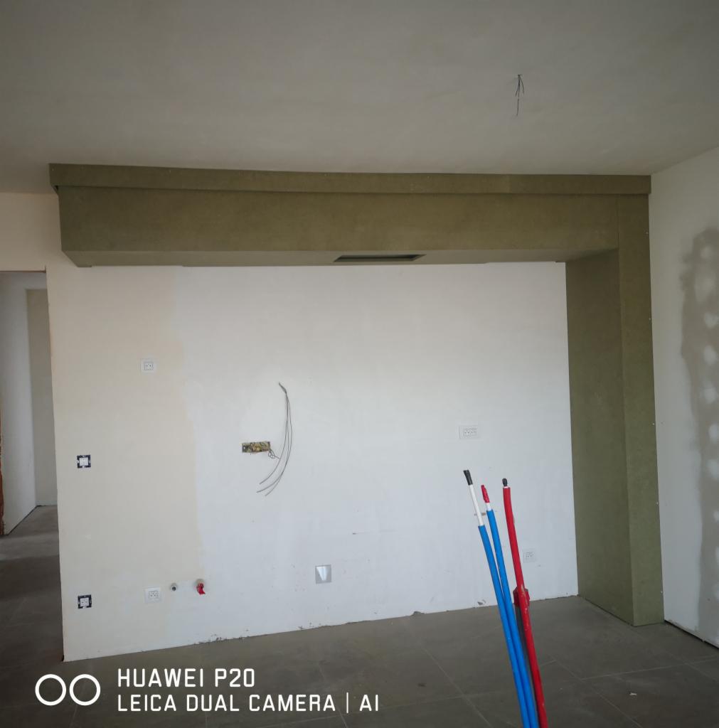 Wnętrze w trakcie prac wykończeniowych, widoczna surowa konstrukcja sufitu podwieszanego z wbudowanym otworem wentylacyjnym, ściany przygotowane do malowania z widocznymi puszkami elektrycznymi...