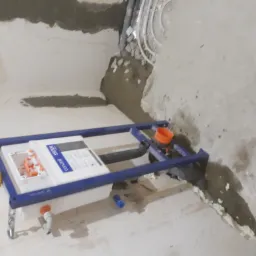 Stelaż podtynkowy WC z niepodłączonymi jeszcze instalacjami wodno-kanalizacyjnymi w surowej łazience przed wykończeniem, widoczne rury doprowadzające wodę i odpływ ścieków.