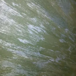 Zielona ściana z dekoracyjnym efektem malowania, widoczne pociągnięcia pędzla i delikatny połysk.