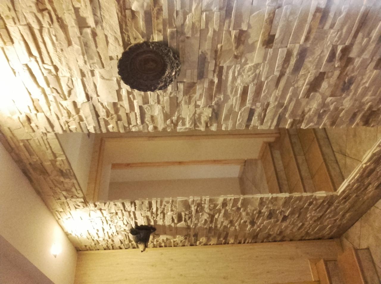 Dekoracyjny sufit z okładziny imitującej kamień, z wbudowanym oświetleniem i ozdobnym elementem centralnym.