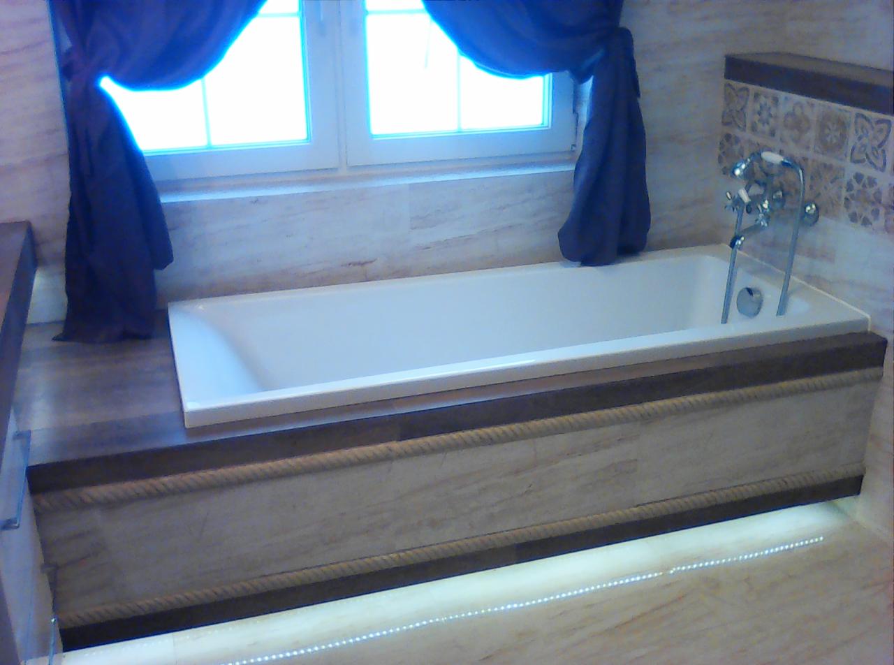 Wanna obudowana panelami z dekoracyjnym motywem liny, podświetlona ledami, z oknem w tle zasłoniętym ciemnymi zasłonami.