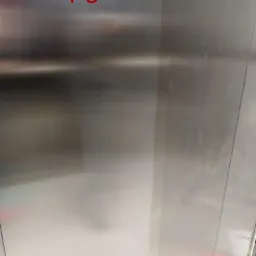 Porównanie czystości metalowej powierzchni windy: część po lewej stronie z napisem 'PO' jest wyraźnie czystsza i bardziej błyszcząca niż część po prawej stronie z napisem 'PRZED', która jest matowa...