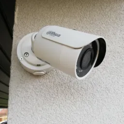 Kamera monitoringu marki Dahua zamontowana na elewacji budynku o gruboziarnistej strukturze.