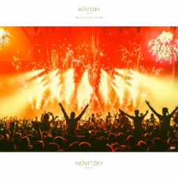 Tłum ludzi z podniesionymi rękami podczas pokazu fajerwerków na koncercie, oświetlenie sceniczne w odcieniach pomarańczy i żółci.