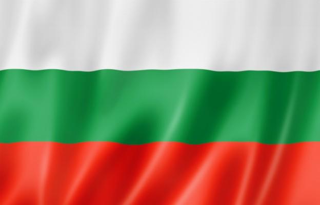 Falująca flaga Bułgarii z poziomymi pasami: białym na górze, zielonym pośrodku i czerwonym na dole.