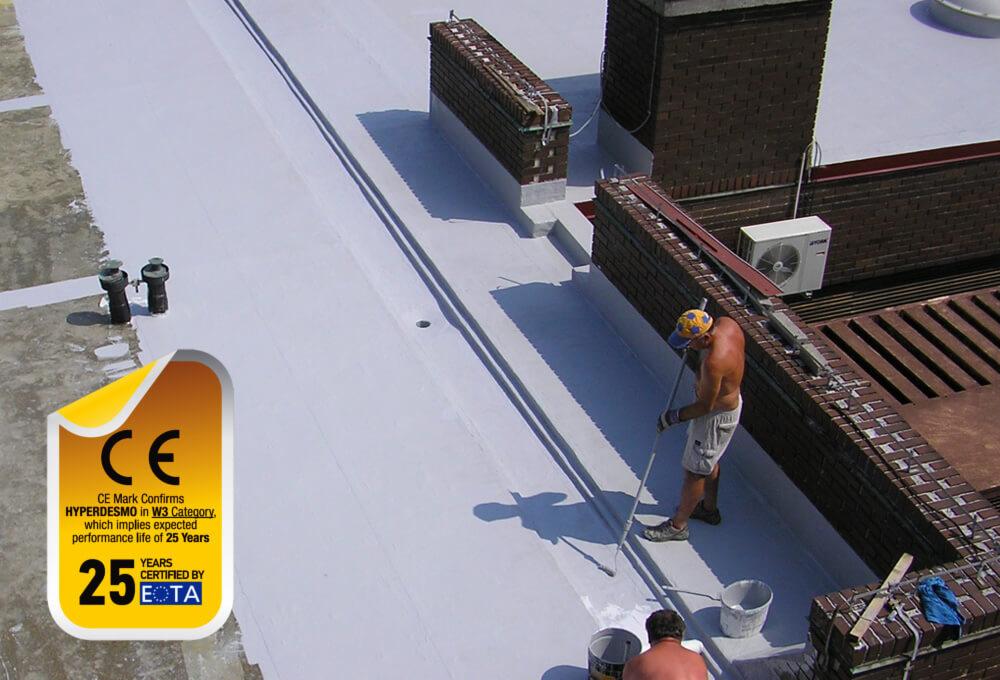 Dwóch mężczyzn wałkuje białą powłokę na płaskim dachu z ceglanymi kominami i certyfikatem CE widocznym w rogu.