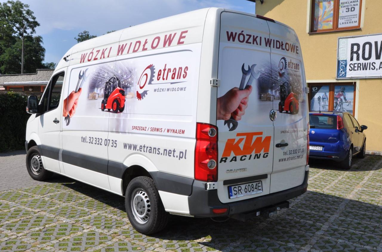 Biały samochód dostawczy z grafiką przedstawiającą wózki widłowe, rękę z kluczem i logo firmy eTrans, zaparkowany na brukowanym placu przed budynkiem.