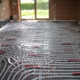 Instalacja ogrzewania podłogowego z rur w kształcie spiral na siatce, widoczne surowe ściany i okno w Krakowie.