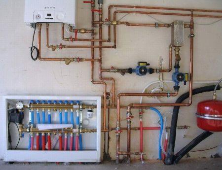 Kompletna instalacja centralnego ogrzewania z kotłem, rozdzielaczem podłogówki z zaworami termostatycznymi, naczyniem przeponowym i pompami obiegowymi zamontowana na ścianie. Widoczne liczne...