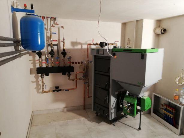 Kotłownia z zainstalowanym kotłem na paliwo stałe z podajnikiem, zbiornikiem wyrównawczym i kompletną instalacją hydrauliczną z miedzianymi rurami.