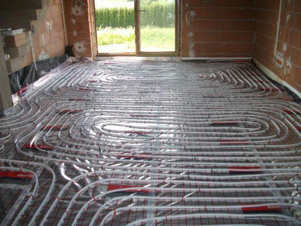 Instalacja ogrzewania podłogowego z rur w kształcie spiral na siatce, widoczne surowe ściany i okno w Krakowie.