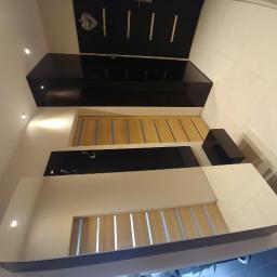 Profil-System - Nowoczesny przedpokój z zabudową w kolorach czerni, bieli i drewna, z oświetleniem punktowym i wieszakami na ścianie.