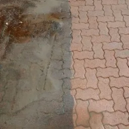 Częściowo wyczyszczona kostka brukowa, widoczna różnica między brudną a czystą powierzchnią, zarys krawędzi czyszczenia.