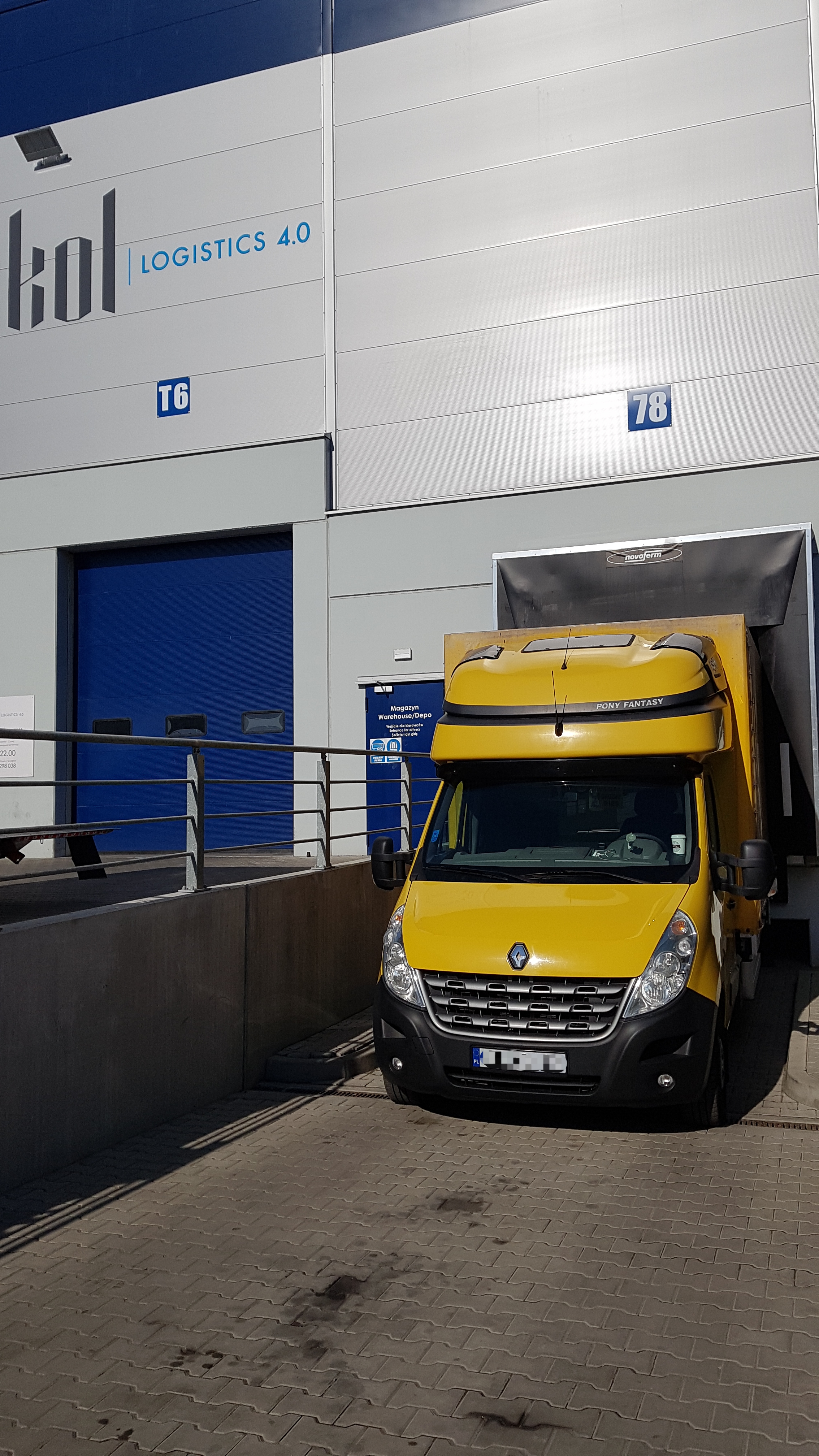 Żółty samochód dostawczy Renault Master z nadbudową Pony Fantasy zaparkowany przed magazynem logistycznym z numerem 78 i niebieską bramą T6.