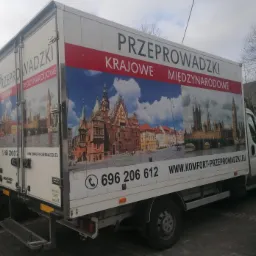 Biała furgonetka z grafiką przedstawiającą zabytki Wrocławia i Londynu oraz napisem 'Przeprowadzki krajowe i międzynarodowe' i numerem telefonu.