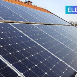 Panel słoneczny na dachu z pomarańczowej dachówki, widoczna drabina i logo firmy Electrum PV w prawym górnym rogu.